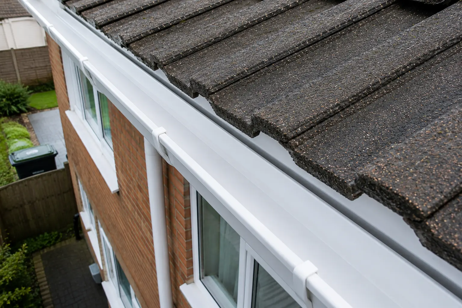 Clean white uPVC gutters and dark roof tiles on a residential home in Bournemouth after professional maintenance.