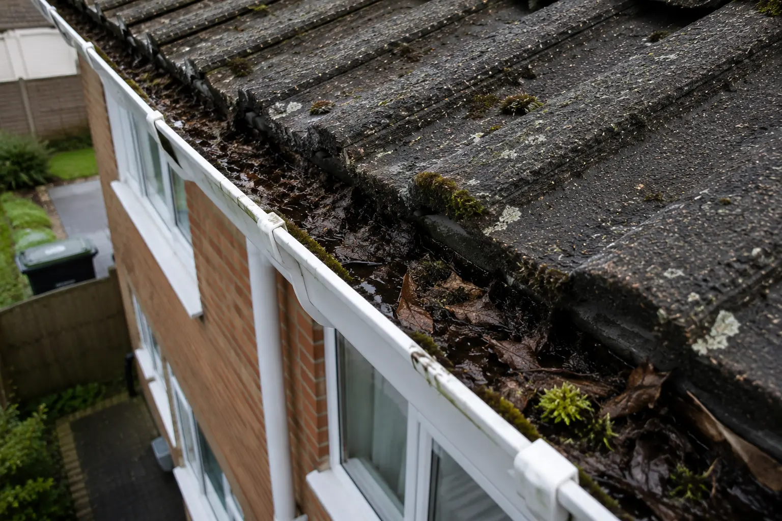 Gutter Cleaning Service Roof Cleaning Bournemouth Blocked gutter filled with leaves and moss on a residential roof in Bournemouth.